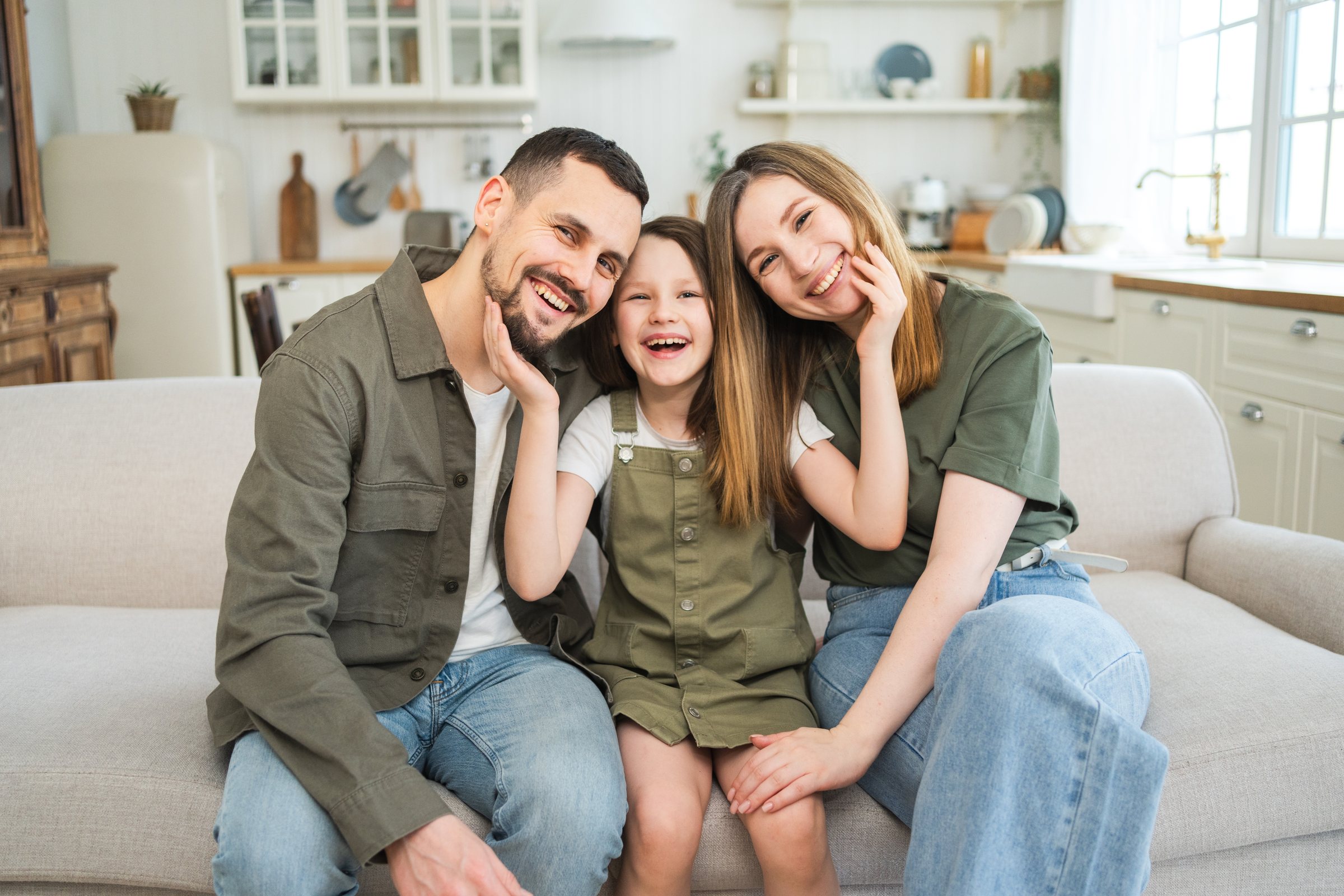 Smiling parents and their daughter sitting together at home
